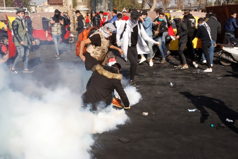 Iraqi demonstrators try to extinguish tear gas during the ongoing anti-government protests in Baghdad