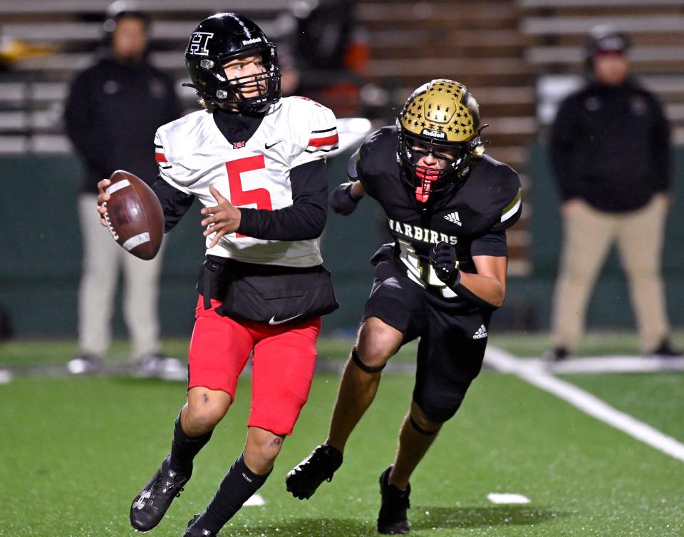 El Paso Hanks quarterback Marcus Porras looks for an open receiver as Abilene High linebacker Caden Rainwater closes in looking for a sack during Thursday’s 5A Div. I bi-district playoff in Abilene.