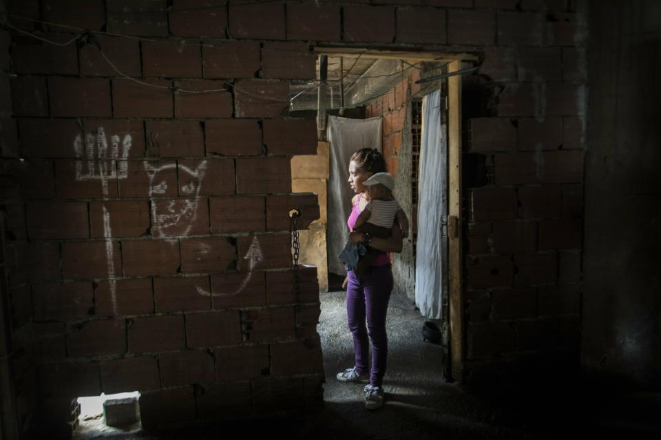Yubaisy Garcia stands outside her room holding her 4-month-old son Jean Pierre, in a building occupied by homeless families in Caracas, Venezuela, Monday, May 6, 2019. Venezuela is in the midst of a growing political and economic crisis as, the U.S.-backed Juan Guaidó declared himself interim president in January, saying President Nicolas Maduro's re-election last year was rigged and one in a series of increasingly authoritarian steps since he replaced the late Hugo Chávez in 2013 as president. (AP Photo/Rodrigo Abd)