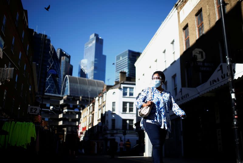 A woman wearing a protective face mask walks along the Petticoat Lane Market, amid the coronavirus disease (COVID-19) outbreak, in London