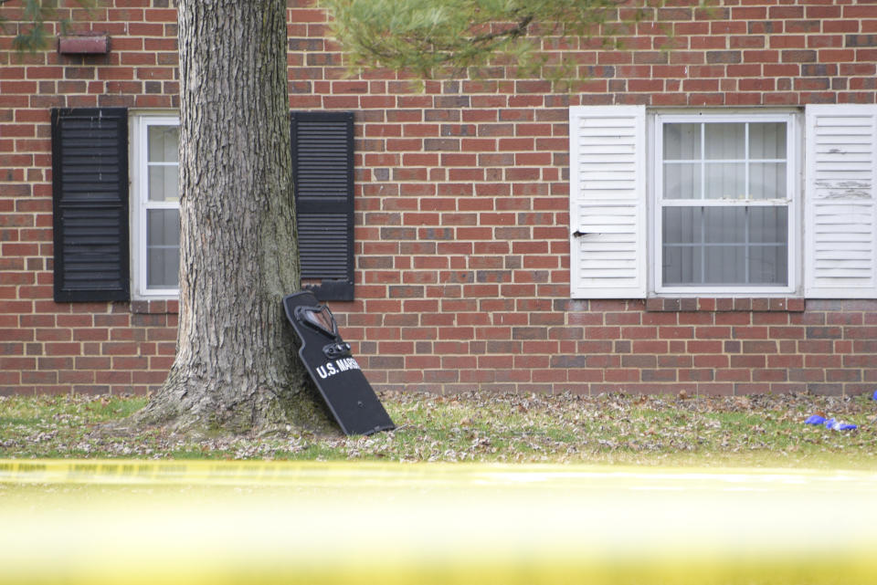 A U.S. Marshals' shield leans against a tree outside an apartment complex at the scene of a shooting, Wednesday, Feb. 12, 2020, in Baltimore. Two law enforcement officers with a fugitive task force were injured and a suspect died in the shooting, the U.S. Marshals Service said. (Ulysses Muñoz/The Baltimore Sun via AP)