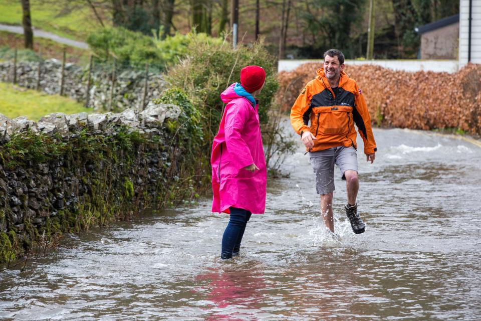 Flooding caused by Storm Ciara at Rothay Bridge in Ambleside, Lake District, UK, with Justin Rowlatt, the BBC environment corespondent wading along a