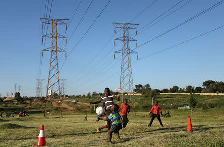 Boys use traffic cones as goal posts as the play soccer below electricity pylons in Soweto, South Africa, February 20, 2019. REUTERS/Siphiwe Sibeko