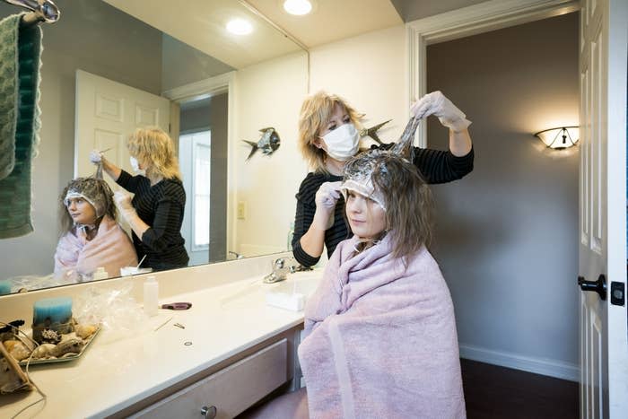 A mom cutting her child's hair in their bathroom