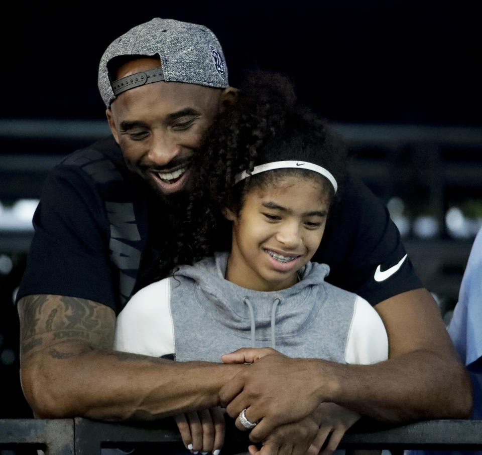 FILE - In this July 26, 2018, file photo former Los Angeles Laker Kobe Bryant and his daughter Gianna watch during the U.S. national championships swimming meet in Irvine, Calif. Federal investigators say wreckage from the helicopter that crashed last month and killed Bryant, his daughter and seven others did not show any outward evidence of engine failure, the National Transportation Safety Board said Friday, Feb. 7, 2020. (AP Photo/Chris Carlson,File)