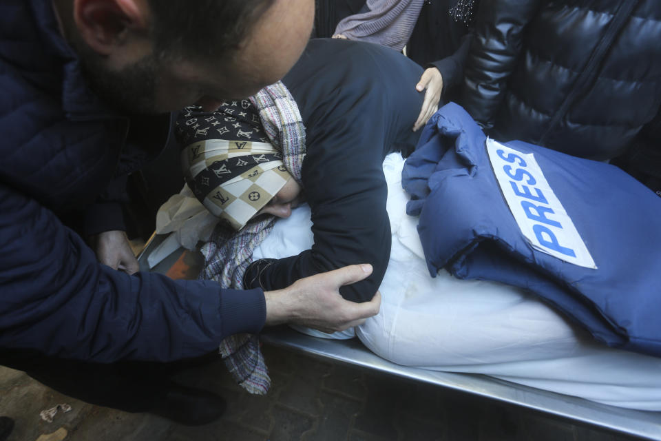 A relative mourns Palestinian journalist Akram Al-Shafi'i, killed in the Israeli bombardment of the Gaza Strip, in a morgue of the European Gaza Hospital in Rafah, Saturday, Jan. 6, 2024. (AP Photo/Hatem Ali)