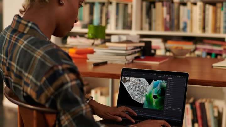 A person sitting at a desk using a MacBook Pro on their lap.