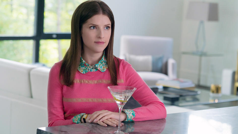 Anna sitting with a drink, wearing a sweater