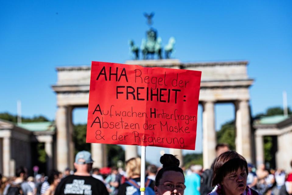 Ein Schild mit der Aufschrift "AHA Regel der Freiheit: Aufwachen, Hinterfragen, Absetzen der Maske & der Regierung" ragt aus der Menschenmenge bei der Demonstration gegen Corona-Maßnahmen vor dem Brandenburger Tor.<span class="copyright">Paul Zinken / dpa</span>