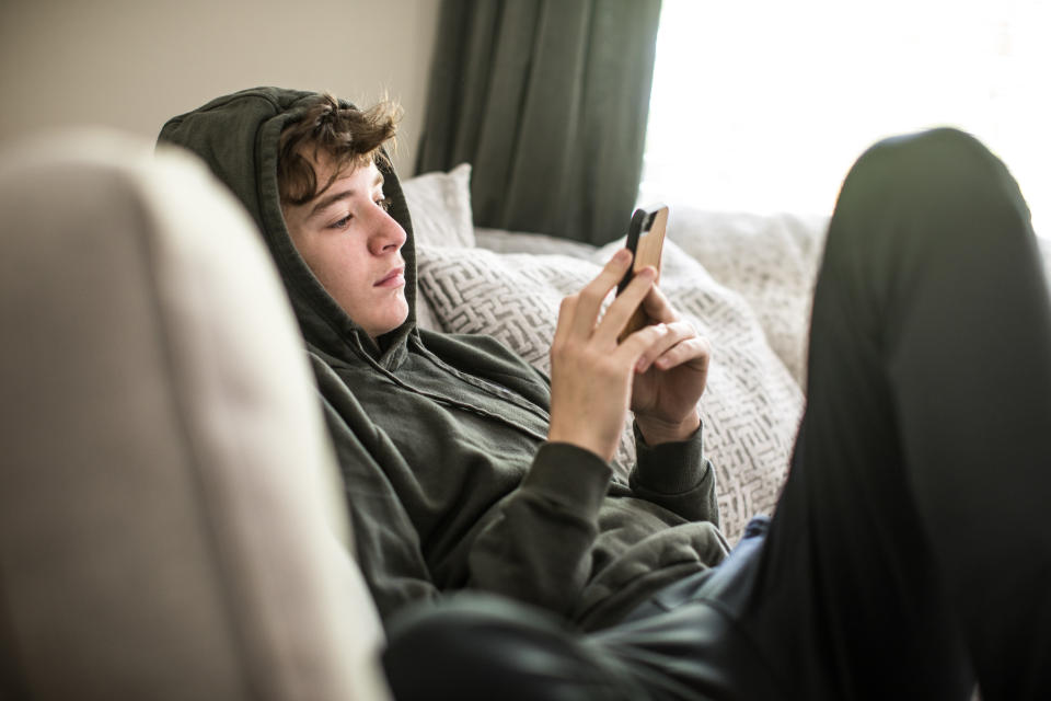 Teenage boy using smartphone at home