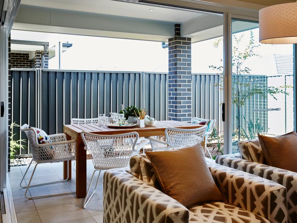 outdoor dining area with white chairs flowing into living room with brown and beige seats