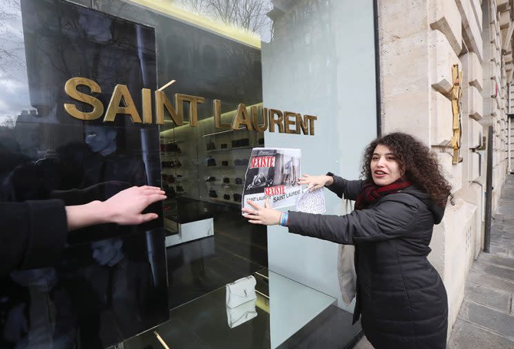 An activist puts a sign that reads “sexist” on the window of an Yves Saint Laurent shop in Paris. (Photo: Jacques DeMarthon/AFP/Getty Images)