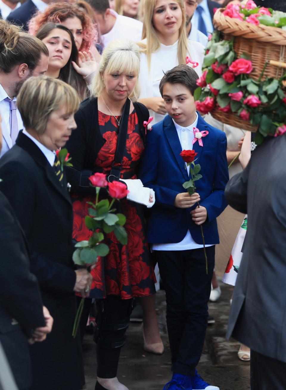 Mum Lisa Roussos and brother Xander look on as the coffin arrives at Manchester Cathedral (PA Images)