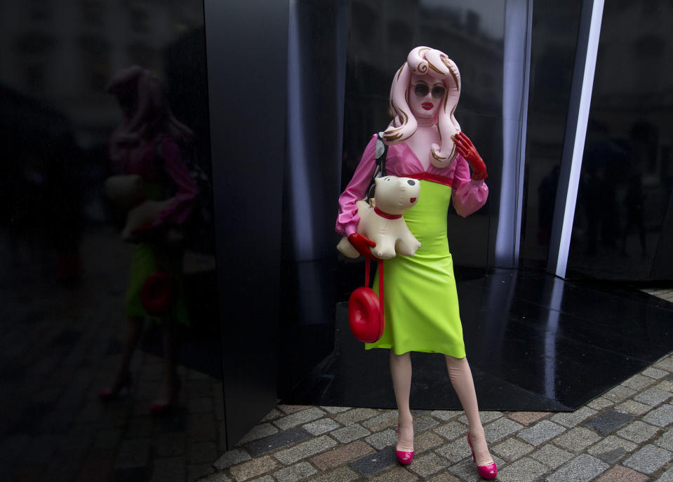 A woman wearing plastic clothes poses for pictures on the first day of London Fashion Week, in London, Friday, Feb. 14, 2014. (AP Photo/Alastair Grant)