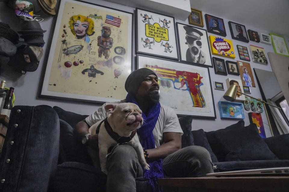 El pintor Guy Stanley Philoche y su perro Picasso fotografiados en el pequeño departamento del artista en el East Harlem de Nueva York el 19 de noviembre del 2020. (AP Photo/Bebeto Matthews)