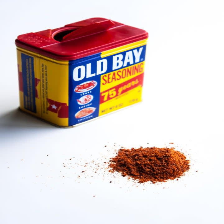 Old Bay seasoning on a white countertop, next to a spice jar of it