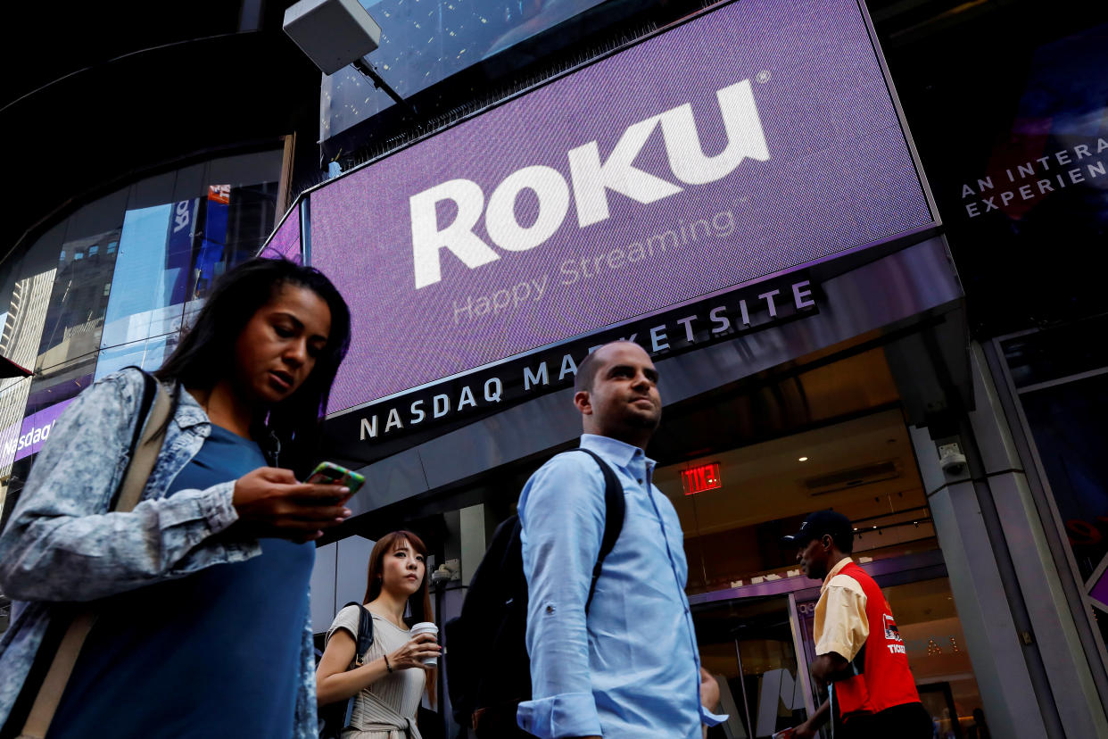 People pass by a video sign display with the logo for Roku Inc, a Fox-backed video streaming firm, that held it's IPO at the Nasdaq Marketsite in New York, U.S., September 28, 2017. REUTERS/Brendan McDermid