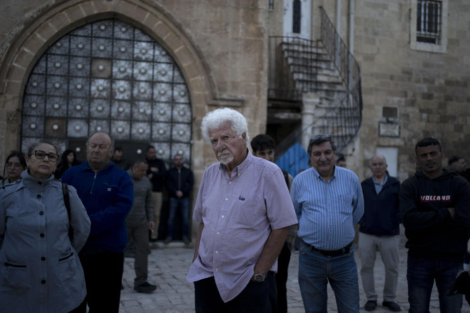 Garo Nalbandian, an 80-year-old photojournalist, center, listens to a speaker during an Armenian community protest of a contentious deal that stands to displace him and other residents and cede some 25 percent of the Armenian Quarter in the Old City of Jerusalem, Friday, May 19, 2023. "If they sell this place, they sell my heart," he said of the Ottoman-era barracks where he has lived for five decades among a dwindling community of Armenians. (AP Photo/Maya Alleruzzo)