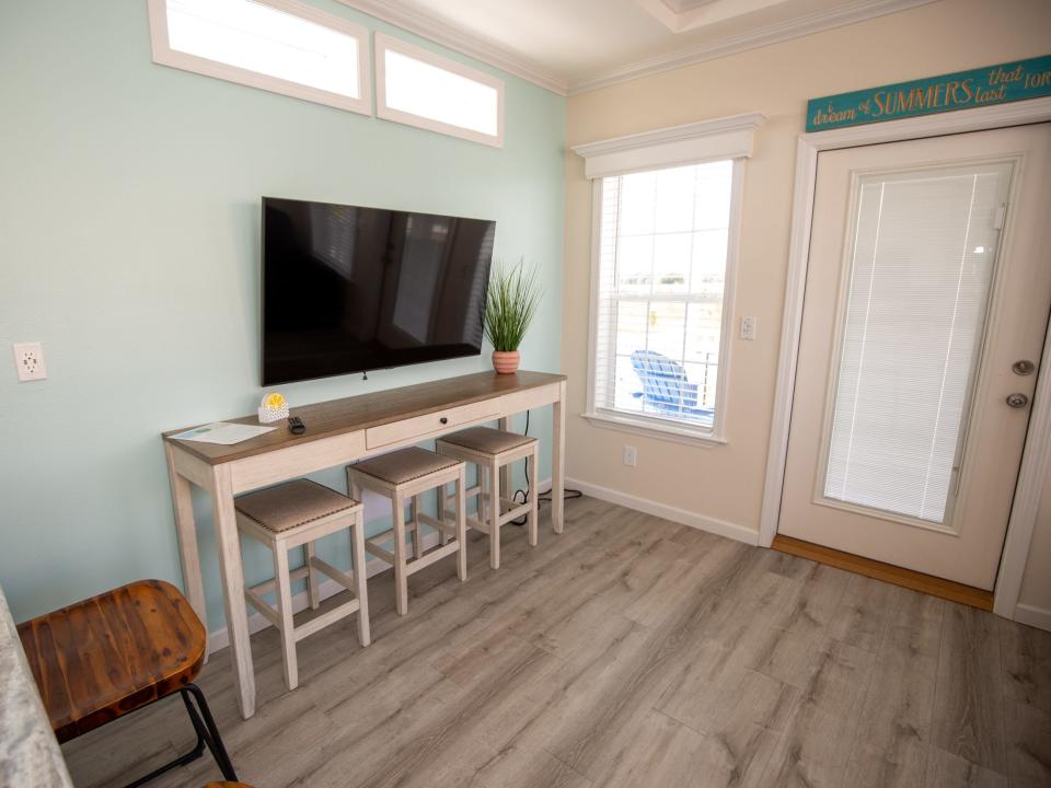 A TV hung on the wall above a table with chairs next to a door.