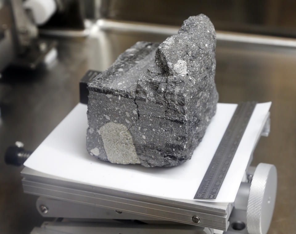 A regolith breccia rock of sintered lunar soil, dating 3.2 billion years old and collected by Apollo 15, is displayed in a pressurized nitrogen-filled case inside the lunar lab at the NASA Johnson Space Center Monday, June 17, 2019, in Houston. (AP Photo/Michael Wyke)