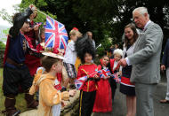 <p>Prince Charles, Prince of Wales, meets 3-year-old Monty Shepherd (second from left), who is dressed as a corgi, and other children in costume, as he attends a street party. (Photo by Geoff Caddick — WPA Pool/Getty Images) </p>