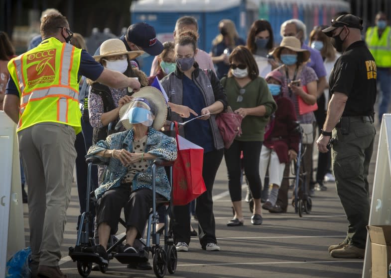 Anaheim, CA - January 13: Officials take the temperature of Orange County active Phase 1A (critical and healthcare workers) residents as they line up to enter large tents at Orange County's first large-scale vaccination site to receive the Moderna COVID-19 vaccine in the Toy Story parking lot at the Disneyland Resort in Anaheim Wednesday, Jan. 13, 2021. Orange County supervisors and Orange County Health Care Agency Director Dr. Clayton Chau held a news conference discussing the county's first Super POD (point-of-dispensing) site for COVID-19 vaccine distribution. The vaccinations are at Tier 1A for people who have reservations on a website. The site is able to handle 7,000 immunizations per day. Their goal is to immunize everyone in Orange County who chooses to do so by July 4th. (Allen J. Schaben / Los Angeles Times)