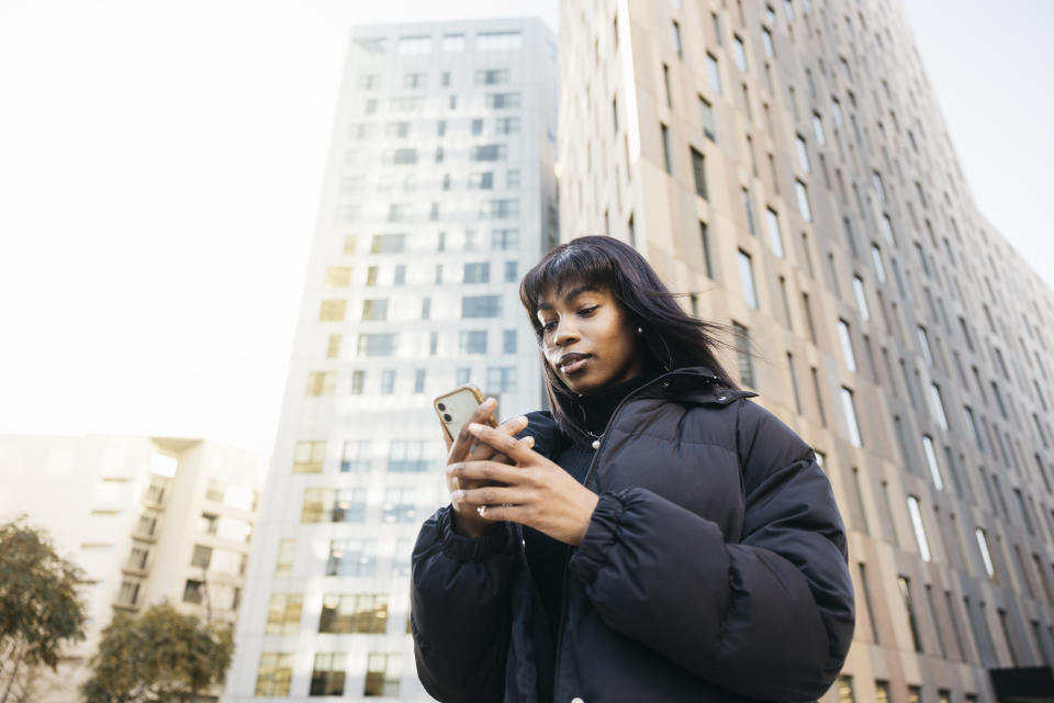 Woman texting while walking down a city street