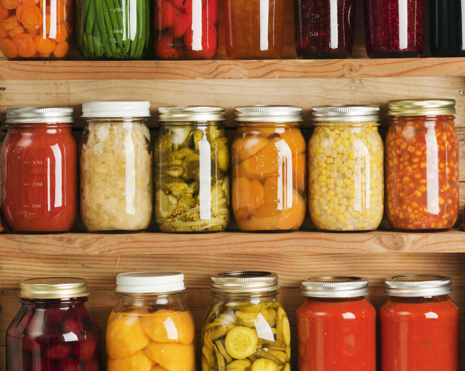 Wooden storage shelves holding home canning vegetable and fruit preserves.