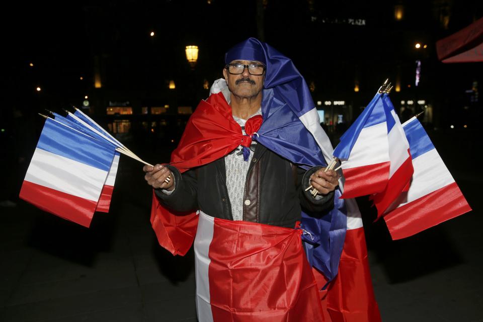 A man holds French flags near the statue at the Place de la Republique on the eve of a ceremony to pay tribute for the victims of shooting attacks in Paris, France, November 26, 2015. The French President called on all French citizens to hang the tricolour national flag from their windows on Friday to pay tribute to the victims of the Paris attacks. (REUTERS/Jacky Naegelen)