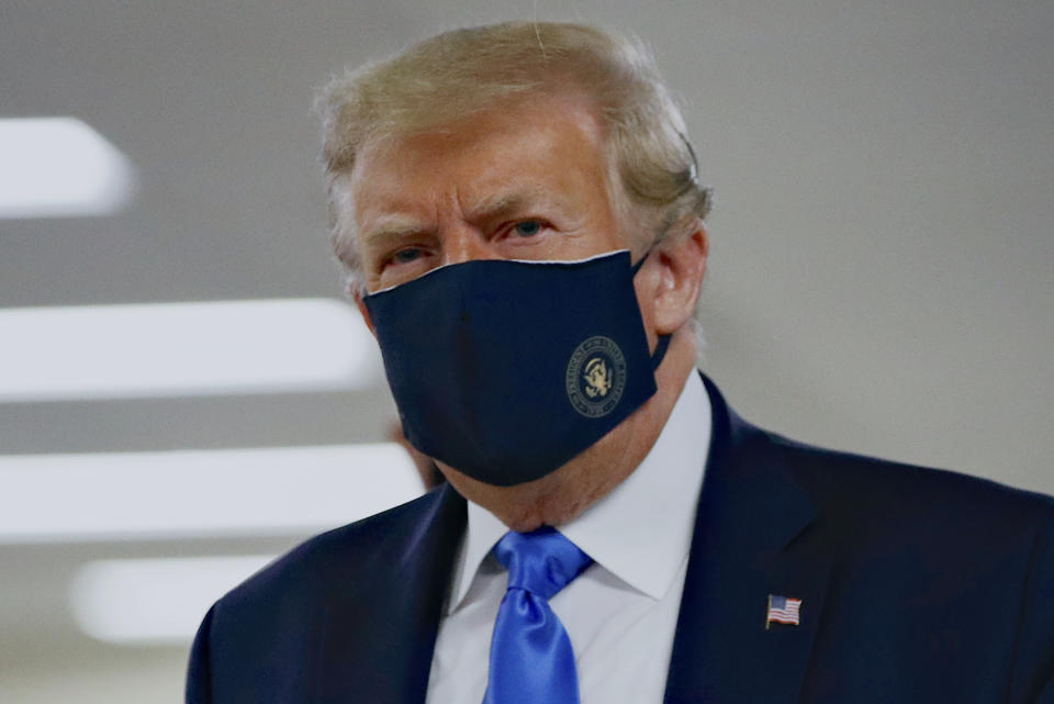 FILE - In this Saturday, July 11, 2020, file photo, President Donald Trump wears a face mask as he walks down a hallway during a visit to Walter Reed National Military Medical Center in Bethesda, Md. When Trump wore a mask publicly for the first time on Saturday, he chose a navy-blue one that bore the presidential seal. It also matched the color of his suit. (AP Photo/Patrick Semansky, File)