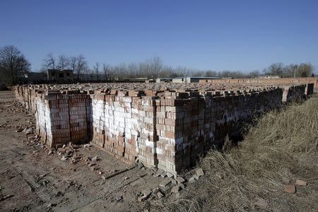 Bricks are placed behind a fence near a closed brick factory on the outskirts of Beijing, China, January, 18, 2016. REUTERS/Jason Lee