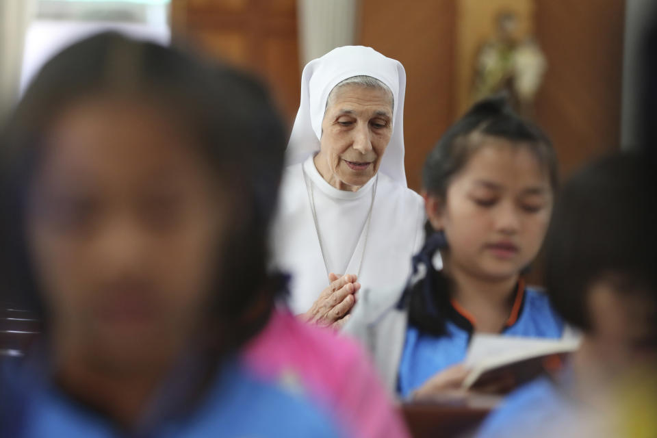 In this Aug. 27, 2019, photo, ST. Mary's School Vice Principal Sister Ana Rosa Sivori, center, and students pray inside a church at the girls' school in Udon Thani, about 570 kilometers (355 miles) northeast of Bangkok, Thailand. Sister Ana Rosa Sivori, originally from Buenos Aires in Argentina, shares a great-grandfather with Jorge Mario Bergoglio, who, six years ago, became Pope Francis. So, she and the pontiff are second cousins. (AP Photo/Sakchai Lalit)