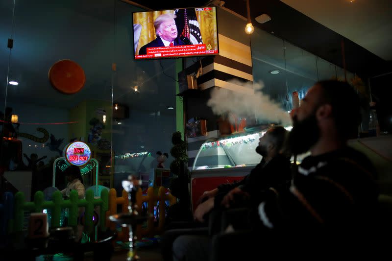 Foto del martes de un grupo de palestinos viendo por TV el discurso del presidente de EEUU, Donald Trump, sobre el anuncio de un plan de paz para Oriente Próximo