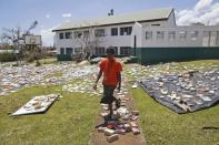 A teacher walks past library books laid out to dry in the sun after the roof of the school library (R) was blown away by Cyclone Pam at the Central School in Port Vila, the capital city of the Pacific island nation of Vanuatu March 18, 2015. REUTERS/Edgar Su