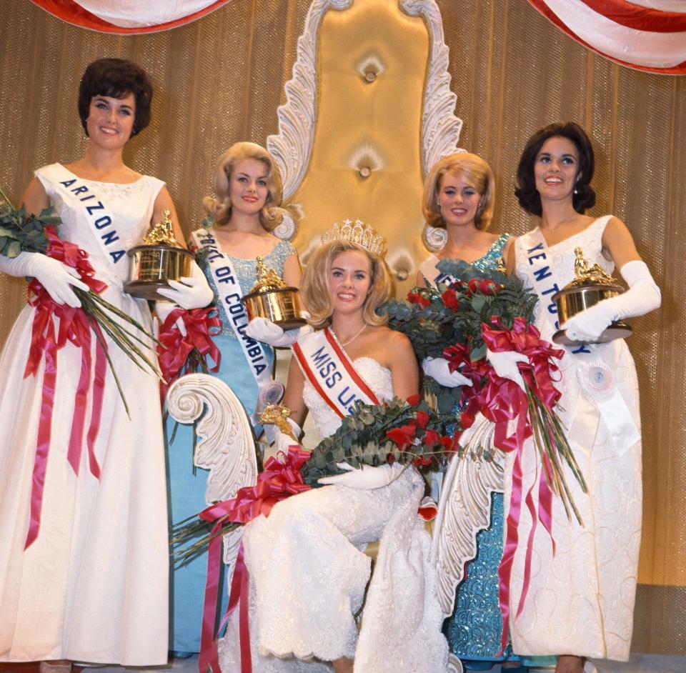 Miss USA 1965 Sue Ann Downey sits on a throne surrounded by her court after winning the pageant.