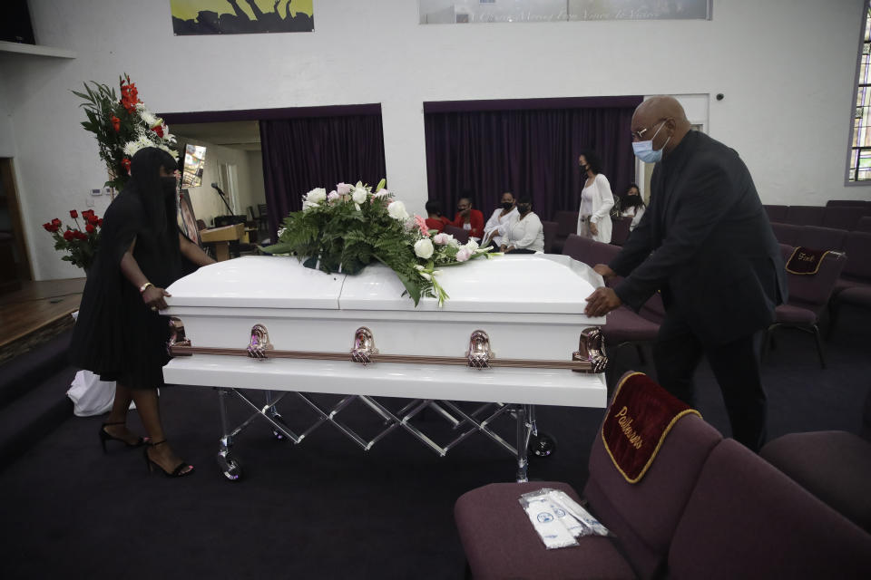 Candy Boyd, left, owner of Boyd Funeral Home, is helped as she brings in the body of Lydia Nunez, who died from COVID-19, during a funeral service at the Metropolitan Baptist Church Tuesday, July 21, 2020, in Los Angeles. When people began dying from the coronavirus in the United States, for a few weeks funeral home owner Boyd declined to receive the remains of such patients. (AP Photo/Marcio Jose Sanchez)