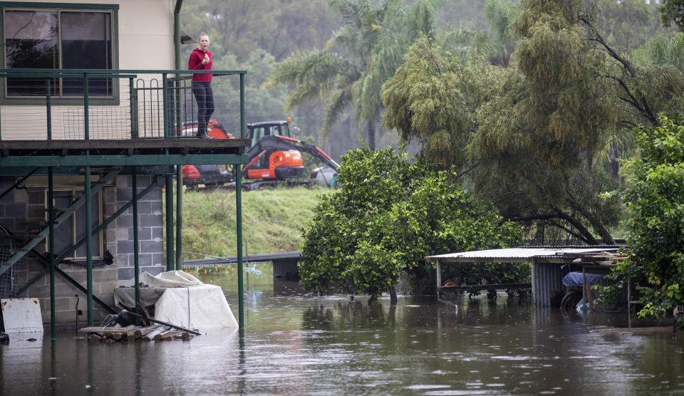 A woman stands on the balcony of her home surrounded by flood waters in Londonderry on the outskirts of Sydney, Australia, Tuesday, March 23, 2021. Hundreds of people have been rescued from floodwaters that have isolated dozens of towns in Australia's most populous state of New South Wales and forced thousands to evacuate their homes as record rain continues to inundate the countries east coast. (AP Photo/Mark Baker)