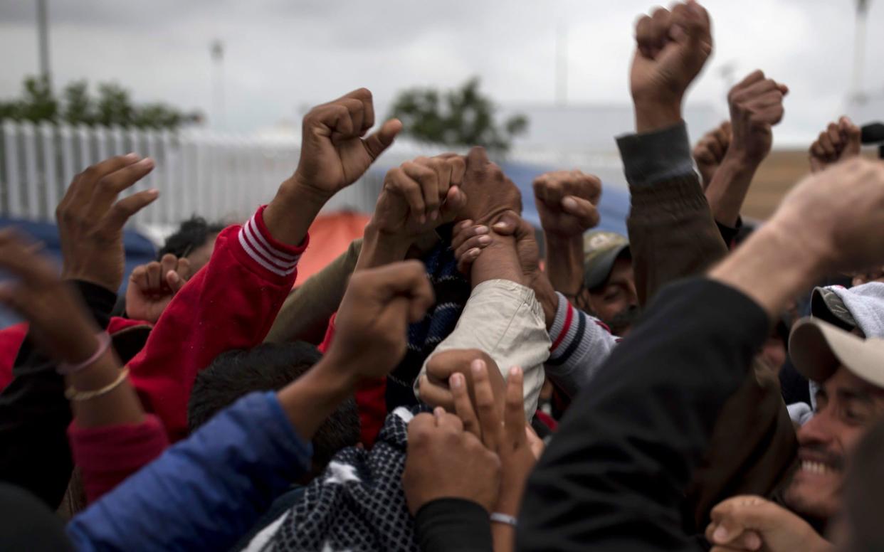 Asylum seekers in Tijuana cheer, in May, on hearing that some of them will be allowed to apply for asylum in the US. Under a new plan, they will wait in Mexico while their claims are processed - AP
