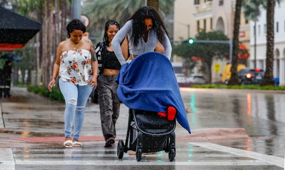 A woman pushing a baby carriage crosses the street along Ponce De Leon Boulevard in Coral Gables during a rain storm on Wednesday, November 15, 2023. Al Diaz/adiaz@miamiherald.com