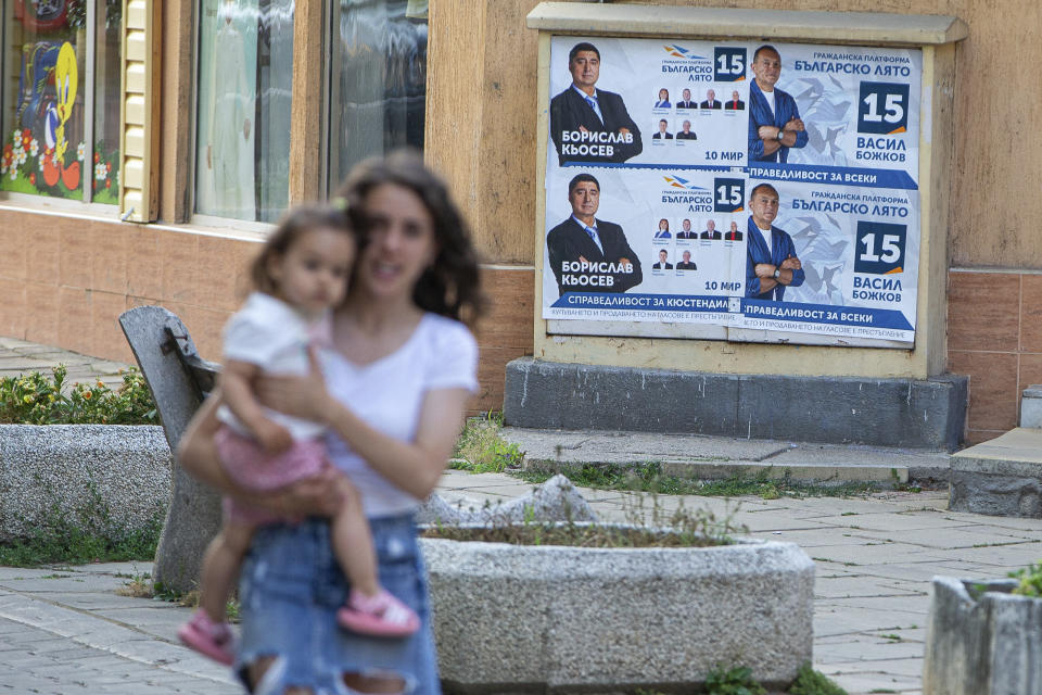 A pedestrian carrying a baby walks past election posters in the town of Kjustendil, Bulgaria on Friday, July 9, 2021. Voters are going to the polls in Bulgaria for the second time in three months this weekend after no party secured enough support in an April parliamentary election to form a government. Former three-time Prime Minister Boyko Borissov’s GERB party performed best in the inconclusive election, but it received only 26 percent of the vote. (AP Photo/Visar Kryeziu)