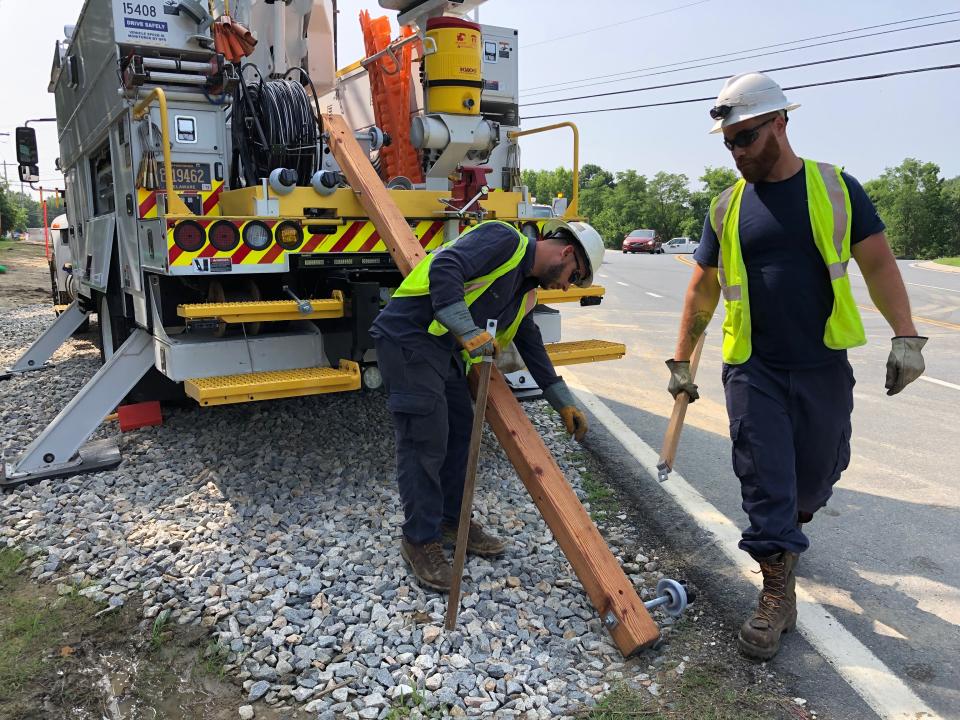 Delmarva Power workers construct a crossbar on-site. A worker will install it at the top of a pole using a bucket truck. Electrical wires will run across the bar.