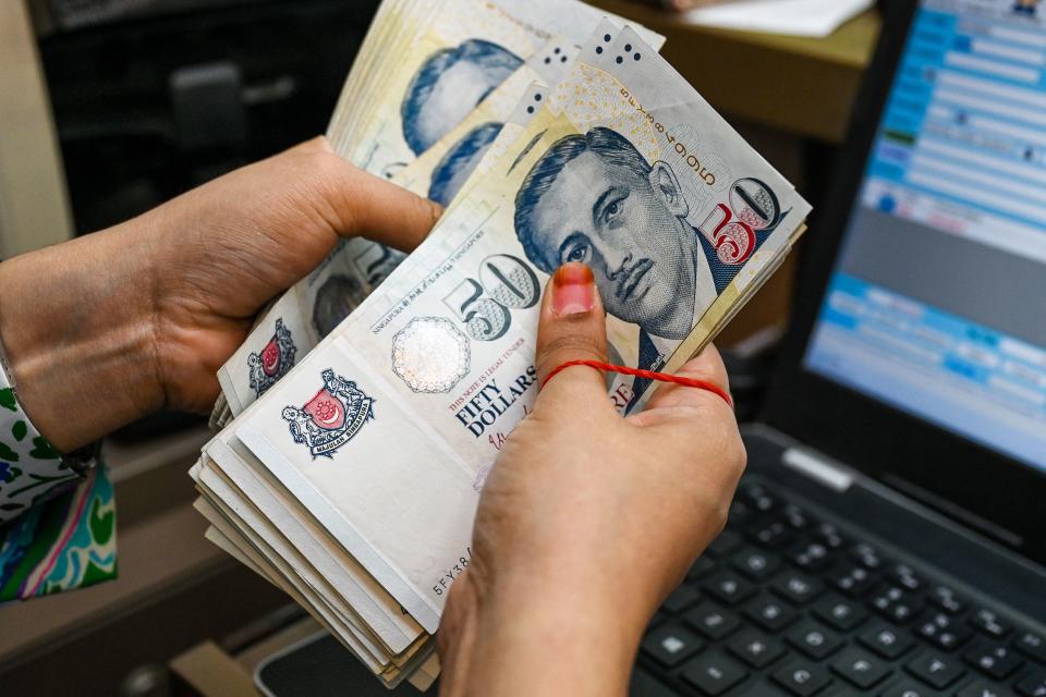 A staff counts Singapore dollar currency notes at a money changer booth at Raffles Place financial business district in Singapore on October 6, 2022. (Photo by Roslan RAHMAN / AFP) (Photo by ROSLAN RAHMAN/AFP via Getty Images)