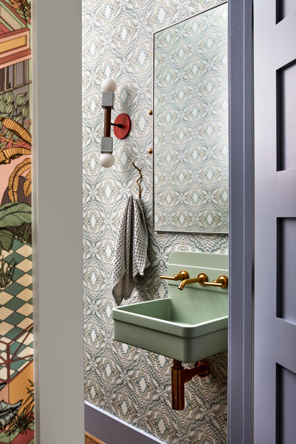The powder room is a meditative hideaway that conjures its own version of the outdoors. As the owners tell it, Flavor Paper’s Placebo Effect wallpaper wasn’t the first choice. “It was supposed to be in a warmer colorway, but we didn’t think that the oranges, reds and blues worked with the cool tones we had decided on for the room. Then, Zoë and her team showed us a recolored version of the wallpaper, paired with a surface-mount Herbert basin by Nood. Suddenly the room became one of our favorite moments in the entire house,” says one half of the couple. A Farren mirror by CB2 emblazons one wall. The sconce is Cedar & Moss’s Stanton marque.