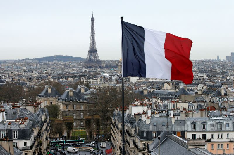 FILE PHOTO: A French flag waves above the skyline as the Eiffel Tower and roof tops are seen in Paris, France