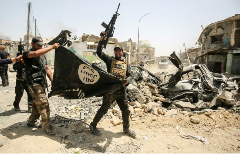 Members of the Iraqi forces cheer as they carry an upside-down flag of the Islamic State (IS) group in Mosul on July 2, 2017