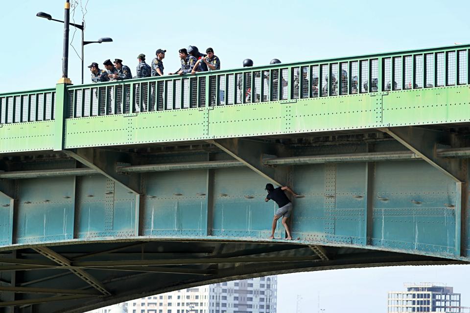 An anti-government protester tries to sneak while Iraqi security forces close the bridge leading to the Green Zone during a demonstration in Baghdad, Iraq, Saturday, Oct. 26, 2019. On Friday protesters tried to push their way toward the heavily-fortified Green Zone which houses government and diplomatic offices. Protesters also attacked offices of l Iran-backed militias. (AP Photo/Hadi Mizban)