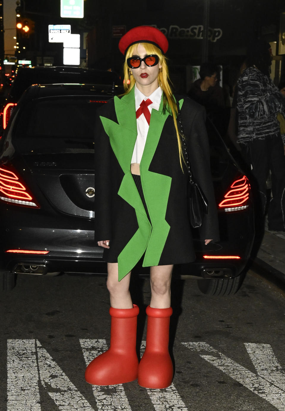 A guest is seen wearing a black and green jacket, white top, red beret, and the big red boots outside the Collina Strada show during New York Fashion Week on Feb. 10, 2023