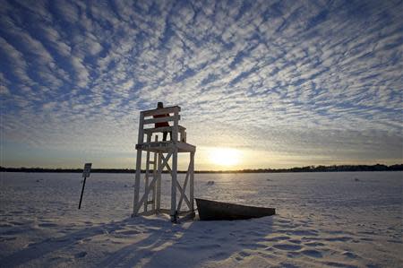 Jennifer Berry watches the sunset from a lifeguard chair at a beach on Lake Calhoun in Minneapolis, January 7, 2014. REUTERS/Eric Miller