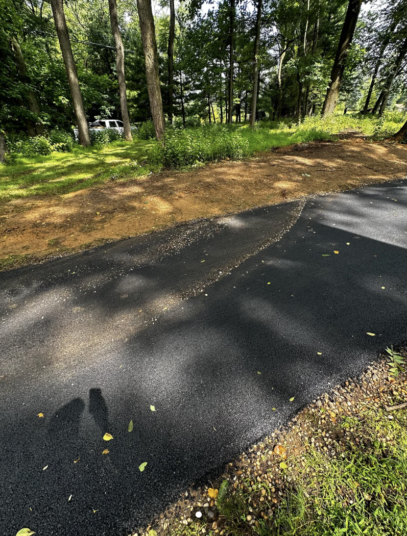 A Reddit post showing a driveway with newly laid asphalt and a patch covered with gravel pushed onto the new driveway. Text summarizes user experience with asphalt