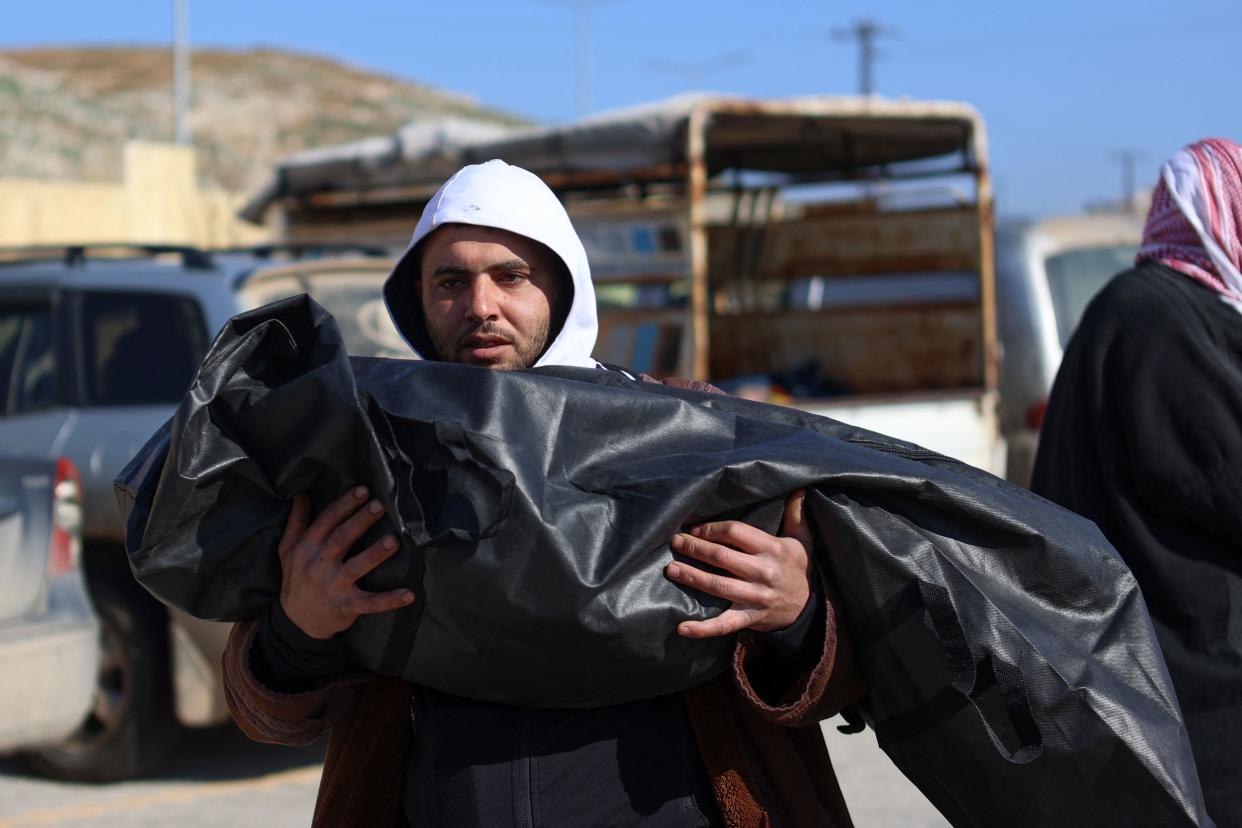 A Syrian man carries the body of a relative killed in Turkey's Hatay region